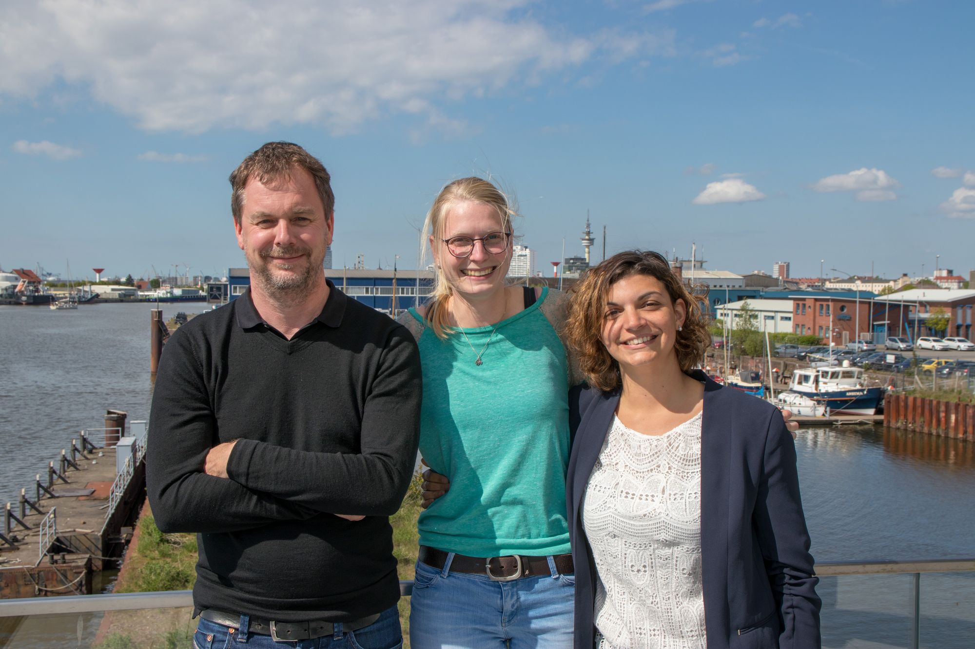 Leiter und zwei Mitarbeiterinnen des Arbeitspakets 1 vor dem Bremerhavener Hafen